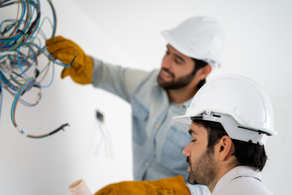Electrician mounting wiring for electric sockets on the construction site of a new house,Construction concept.
