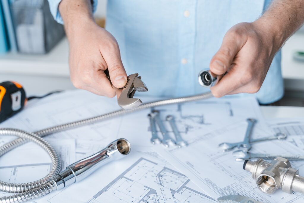 Plumbing project in house.Drawing,diagrams,plan of water supply of apartment,building.Man repairer making repairs at home.Devices,accessories, hose,tap,adjustable wrench,pressure reducer,tape measure.